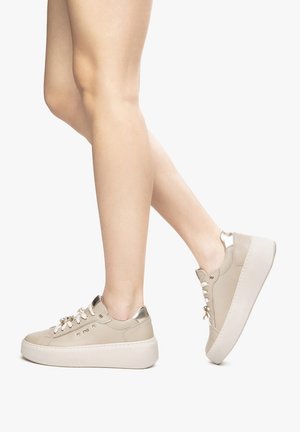 Sneaker platform beige con accenti metallici e lacci, caratterizzate da una tomaia in pelle liscia e una suola texture. Design a profilo basso.