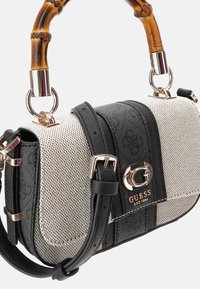 Petit sac à main rectangulaire avec un corps en maille beige, des accents en cuir noir et une poignée en bambou. Présente un logo doré et une bandoulière ajustable.