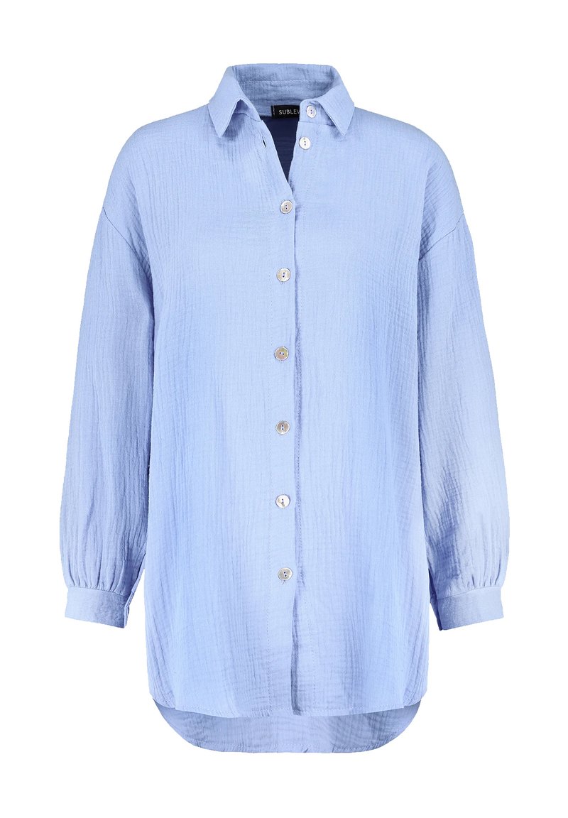 Light blue, button-up shirt made of textured fabric. Features a collar, long sleeves with elastic cuffs, and a rounded hem.