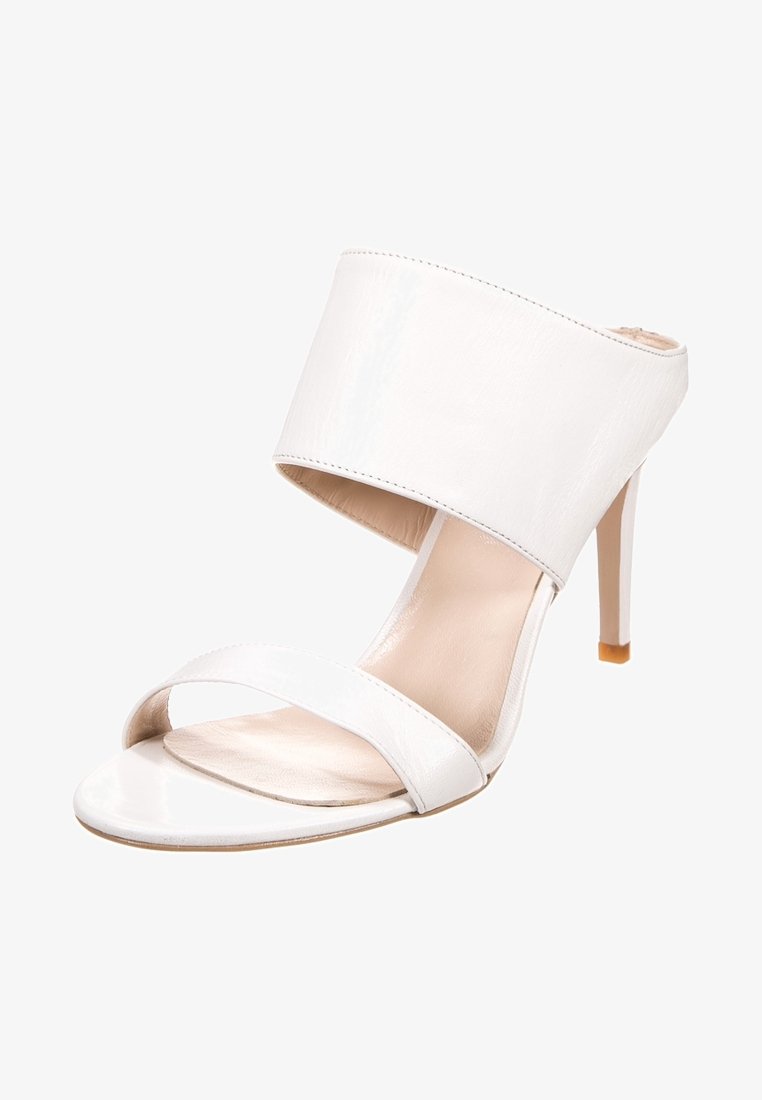 Mule blanche à talon haut avec large sangle à la cheville et fine sangle à l'orteil, pied ouvert, et talon stiletto.