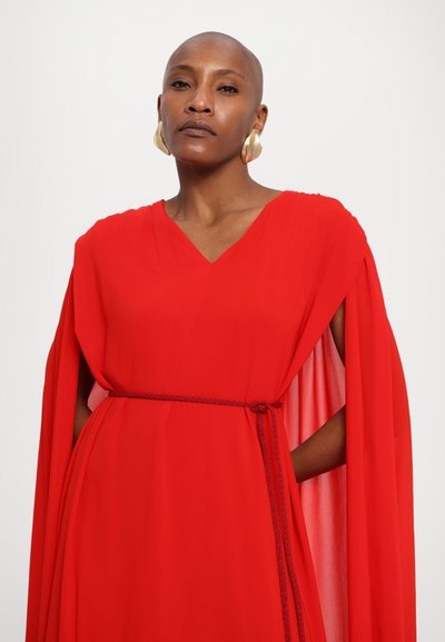 Red chiffon dress with a V-neck, flowing cape sleeves, and a braided belt at the waist. Features a smooth, draped texture. Gold earrings.