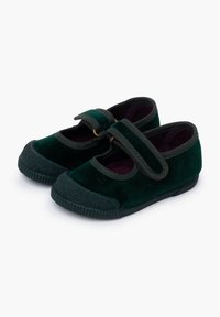 Zapatos infantiles de terciopelo verde con una correa ancha y herrajes dorados. Punta redondeada con suela de goma y cubrepunta texturizado.