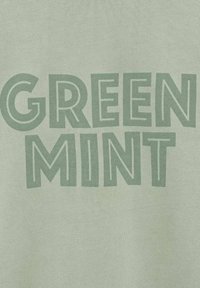 Lichtgroene stof met de tekst "GREEN MINT" in donkerder groene, vetgedrukte, blokletters met variërende dikte en stijl.