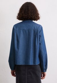Dunkelblaue Jeanshemden mit Knöpfen, langen Ärmeln, geradem Schnitt und Rückenfalten für zusätzliche Beweglichkeit. Mit klassischem Kragen und Manschetten.