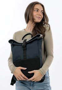 Zaino roll-top in blu navy e nero, realizzato in materiale resistente. Presenta una tasca frontale con zip, spallacci regolabili e un design elegante e minimalista.