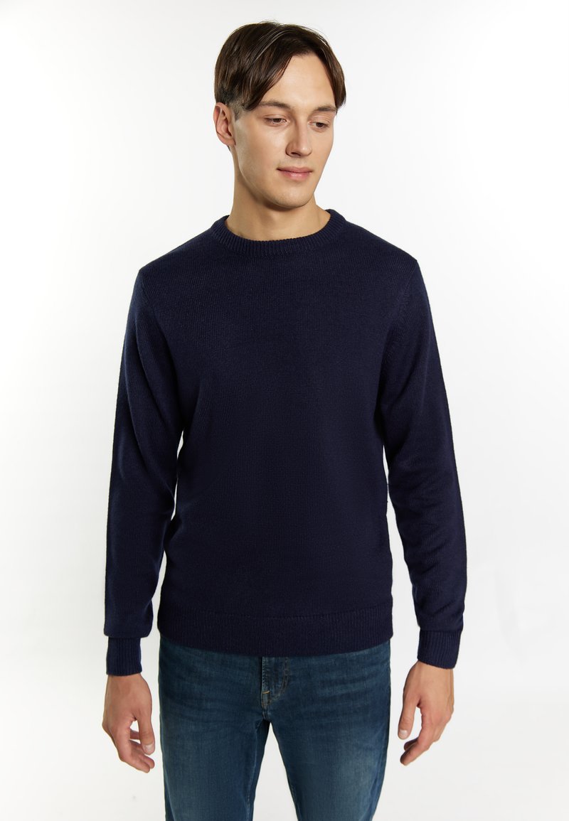 Maglione blu navy realizzato in tessuto a maglia testurizzata, con colletto a girocollo e polsini a coste. Abbinato a jeans blu di denim.