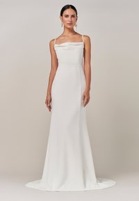 Bela halja dolžine do tal s prilegajočo silhueto, tankimi naramnicami in rahlim nabranim dizajnom ob izrezu, gladka tekstura.