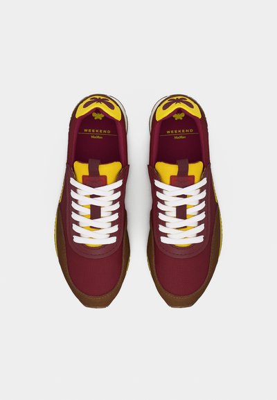 Paire de baskets bordeaux et jaunes avec des lacets blancs, des bouts en cuir marron, et "WEEKEND Max Mara" imprimé à l'intérieur des talons.