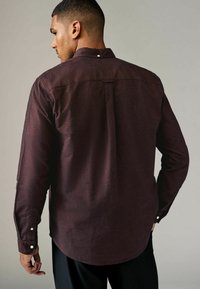 Bordeaux langemouwen shirt van textiel, met een button-down kraag, witte knoopaccenten op de mouwen en een gebogen onderkant.