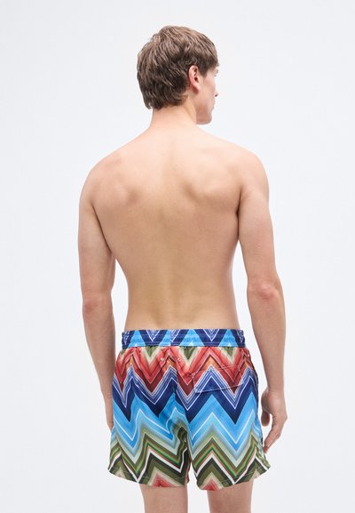 Έγχρωμα μαγιό βερμούδα με ζιγκ-ζαγκ μοτίβο σε αποχρώσεις του μπλε, κόκκινου, πράσινου και πορτοκαλί. Διαθέτουν ελαστική μέση και πίσω τσέπη.