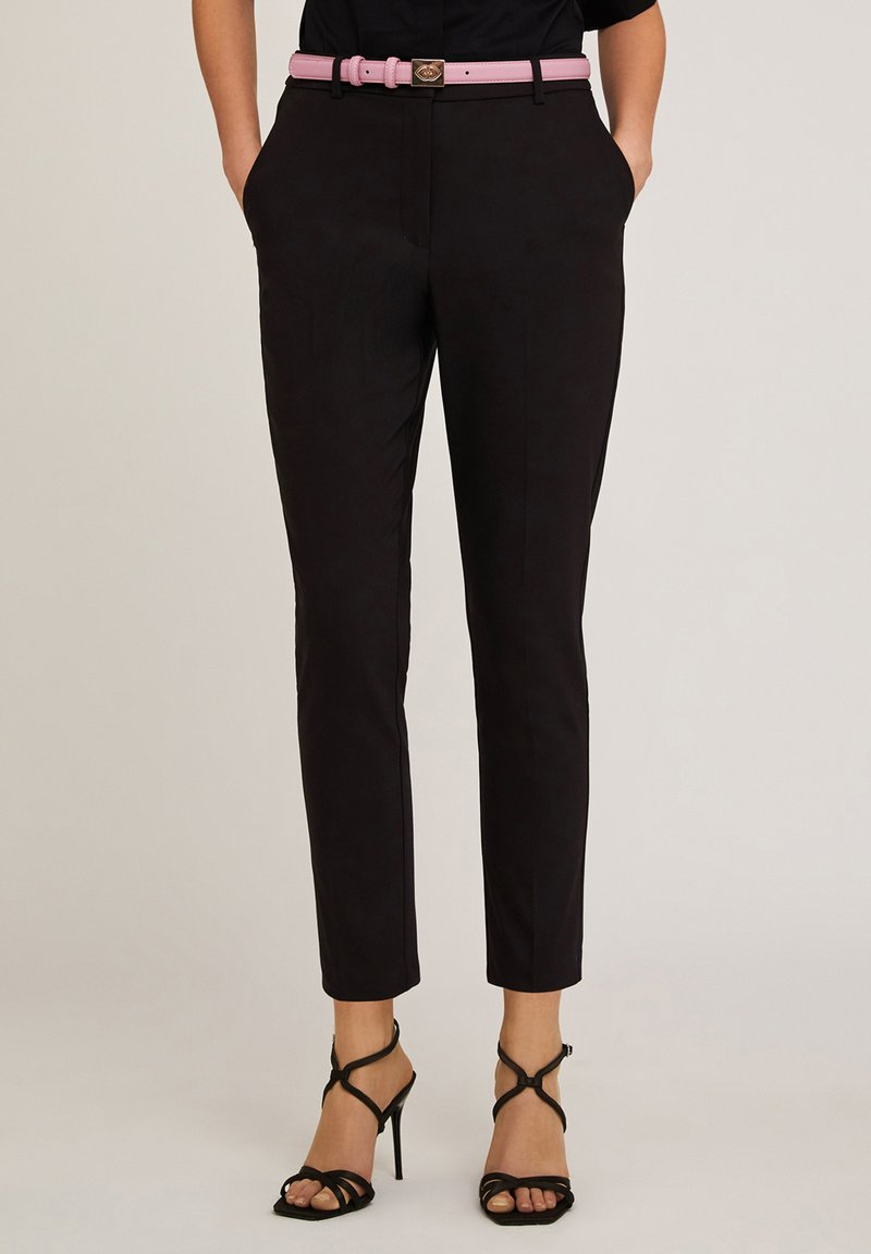 Pantaloni neri su misura con vestibilità slim, dotati di tasche frontali, abbinati a una cintura rosa chiaro e sandali neri con tacco alto e cinturini.