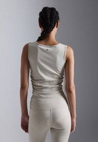 Heleda hallhallia helehall hääratud tank top, millel on kauss kaelus, ribaliselt tekstuur ning kogutud küljed, koos vaste kõrgele vöökohaga legginsidega.
