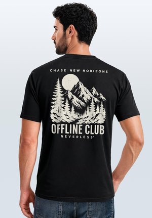 Mann trägt schwarzes T-Shirt mit Berg-, Baum- und Mond-Grafik sowie dem Text "Chase New Horizons Offline Club Neverless" auf dem Rücken.
