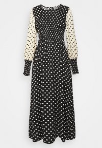Klänning med långa ärmar, svart- och creamfärgade prickar, resårbyst och flytande kjol. Mjukt tyg med kontrasterande ärmar.
