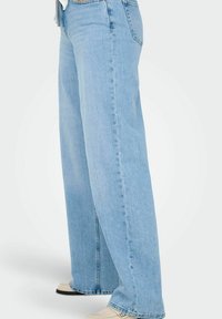 Lyseblå vide jeans laget av denim. Har en rett passform, høy midje og sidespalte nær kanten. Fremhevet med diskrete sømmer.