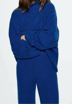 Blue knitted sweater with a relaxed fit, featuring a ribbed texture, wide sleeves, and a crew neckline, paired with matching blue pants.