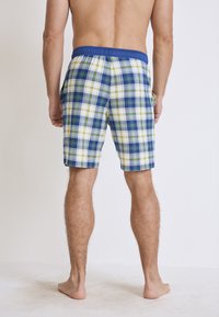 Geruite zwembroek met een blauwe elastische tailleband, voorzien van groene, blauwe en witte blokjes. Inclusief twee zijzakken en een comfortabele pasvorm.