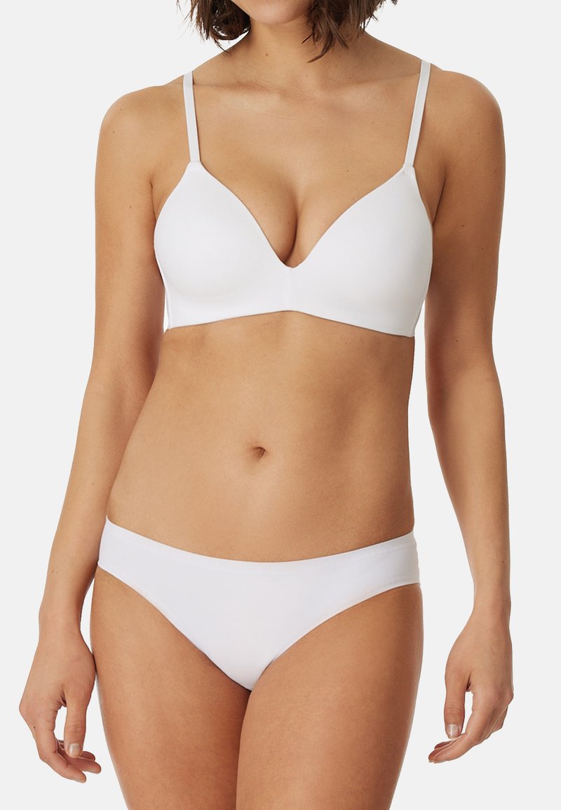 Weißer BH mit tiefem Ausschnitt und dünnen Trägern, kombiniert mit passenden weißen Unterhosen. Glattes Material ohne sichtbare Nähte.