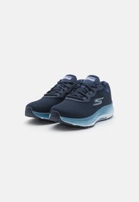 Pantofi sport din plasă de culoare albastru marin, cu talpă de un albastru deschis. Caracteristici includ un guler căptușit, sistem de șireturi frontal și detaliu cu logo pe lateral.