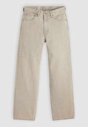 Jean en denim beige à coupe ample, doté de cinq poches, d'une fermeture boutonnée et à glissière, avec des surpiqûres visibles le long des coutures.