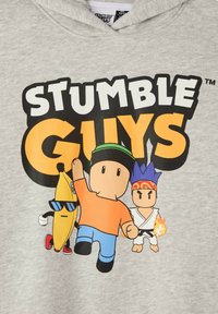 Personaggi stilizzati a cartone animato dal gioco "Stumble Guys": una banana con occhiali da sole, una persona in arancione e blu, e un artista marziale con fiamme.