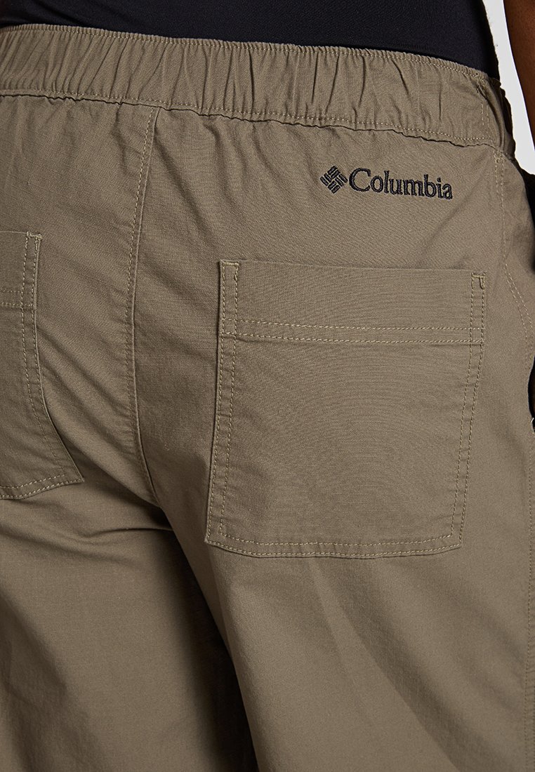 Beżowe szorty z elastycznym pasem, posiadające dwie tylne kieszenie oraz czarne logo Columbia na górnej prawej stronie.