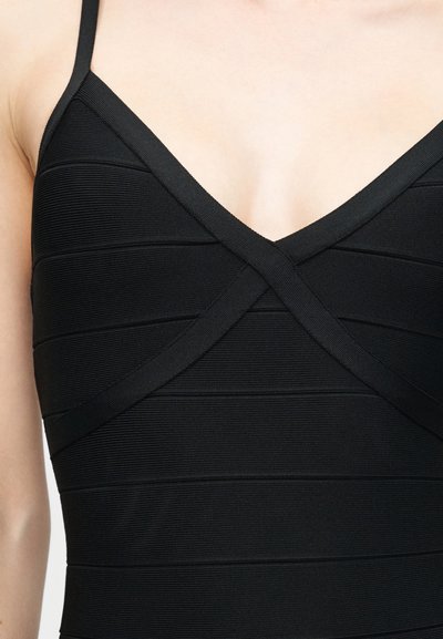 Κοντινό πλάνο ενός μαύρου αμάνικου φορέματος με υφασμένα οριζόντια ριγέ και λαιμόκοψη V με επικαλυπτόμενες υφασμάτινες ταινίες.