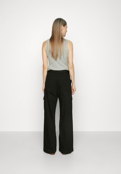Black cargo pants with wide leg design, featuring side pockets and a high waist, paired with a gray sleeveless top in a plain setting.