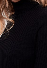 Svart ribbad polotröja med en texturerad yta och en åtsittande design som följer kroppens form.