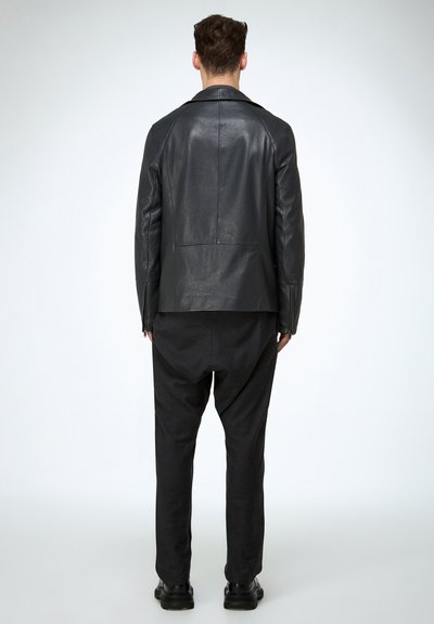 Schwarze Lederjacke mit geradem Schnitt, glatter Struktur und ohne sichtbare Verzierungen, kombiniert mit weiten schwarzen Hosen.