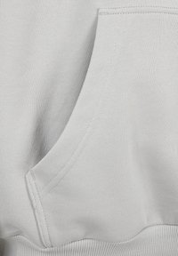 Fondos in primo piano di un tessuto grigio chiaro che mostra una texture a coste e una cucitura della tasca curva.