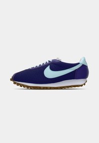 Sapatilha em malha azul escura com swoosh, atacadores e tab de calcanhar em azul claro, entressola branca e sola em borracha de goma, vista lateral sobre fundo branco.