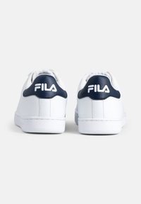 Sneakers bianchi con accenti blu navy, realizzati in pelle liscia. Presentano un design a profilo basso, punta rotonda e collo imbottito con dettagli del logo.