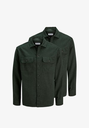 Zwei dunkelgrüne, langärmelige Hemden mit Knöpfen, Kragen und vorderen Klappentaschen, übereinander gelegt vor weißem Hintergrund.