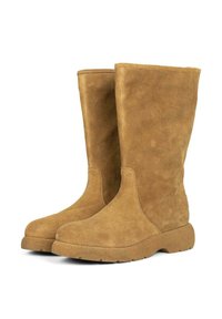 Botas de ante de color marrón claro hasta la rodilla con suela plana y textura suave. Presentan un diseño sin costuras y puntera redondeada, sin hardware visible.