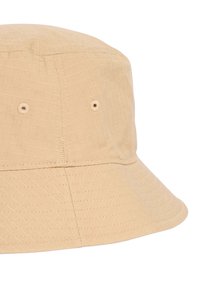 Beige bucket hat made of textured fabric, featuring a wide brim, stitched accents, and ventilation holes for breathability.