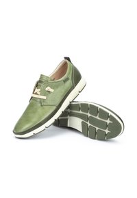 Gröna läderskor med en slät yta, beige snörning och perforerade detaljer. Tjock vit mellansula och texturerad gummisula.