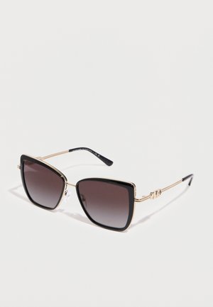 Négyzet alakú napszemüveg fekete átmenetes lencsékkel és vékony arany fémkerettel, világos felületen pihenve.