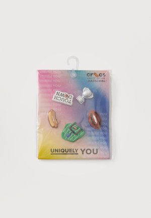 Cinco charms Crocs Jibbitz en una tarjeta multicolor: perrito caliente, trofeo, fútbol, camiseta verde y texto "TOUCH DOWN".