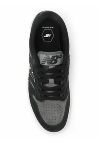 Zapatilla deportiva negra y gris con parte superior de ante y malla, que presenta perforaciones, cordones negros y un logo blanco en el lateral.