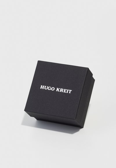 Black cardboard box with a matte finish, featuring the text "HUGO KREIT" in bold white font on the top surface. Square shape.