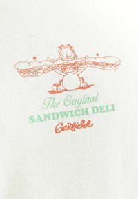 Hvid t-shirt med en orange og grøn grafik af en tegneseriekat, der holder en stor sandwich, med teksten "The Original SANDWICH DELI".