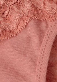 Roze lingerie met een kanten bovenkant met ingewikkelde patronen, zacht textiel en delicate afwerking langs de randen.