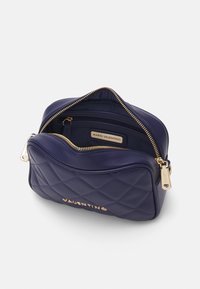 Květovaná námořnická kabelka se zlatými detaily, s hlavním oddílem na zip a malou vnitřní kapsou s nápisem "MARIO VALENTINO."