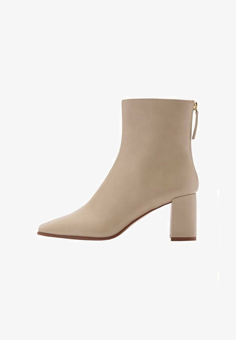 Bottine beige à bout pointu, talon carré, et fermeture éclair arrière avec languette, présentée de profil sur un fond blanc.
