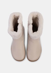 Beige enkelbootjes met een zachte, crèmekleurige nepbontvoering en een gladde leren buitenkant. Eenvoudig design met een ronde neus.