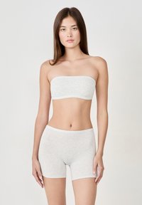 Top bandeau in cotone grigio e pantaloni boxer coordinati; texture liscia, design senza cuciture, finitura morbida, vestibilità a vita media. Estetica minimalista.