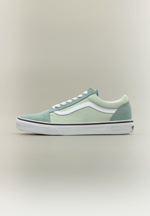 Χαμηλό sneaker σε ανοιχτό πράσινο χρώμα με λευκή πλαϊνή λωρίδα, λευκά κορδόνια και λευκή λαστιχένια σόλα πάνω σε απλό μπεζ φόντο.