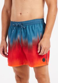 Dames zwempantalons met een gradient patroon dat overgaat van blauw aan de bovenkant naar rood aan de onderkant, met een trekkoord in de taille en een zijlogo.