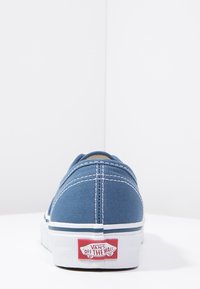 Blue canvas sneaker with white stitching, low-top design, rubber sole, and red "VANS OFF THE WALL" logo on the heel.